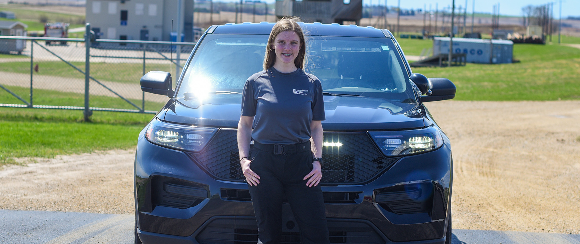 Law Enforcement student standing next to patrol car
