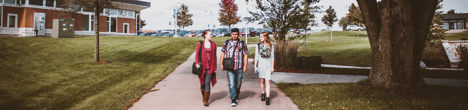 Three students walking down the walkway outside of the Knox Learning Center
