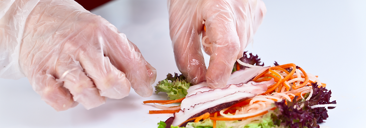 Foodworker gloved hands prepares plate