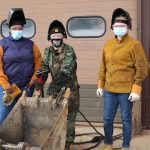 Three students stand by their welding project