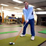 Golf student in the golf lab pretending to tee off.