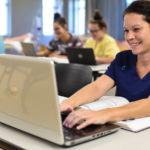 Female student looking at laptop, smiling