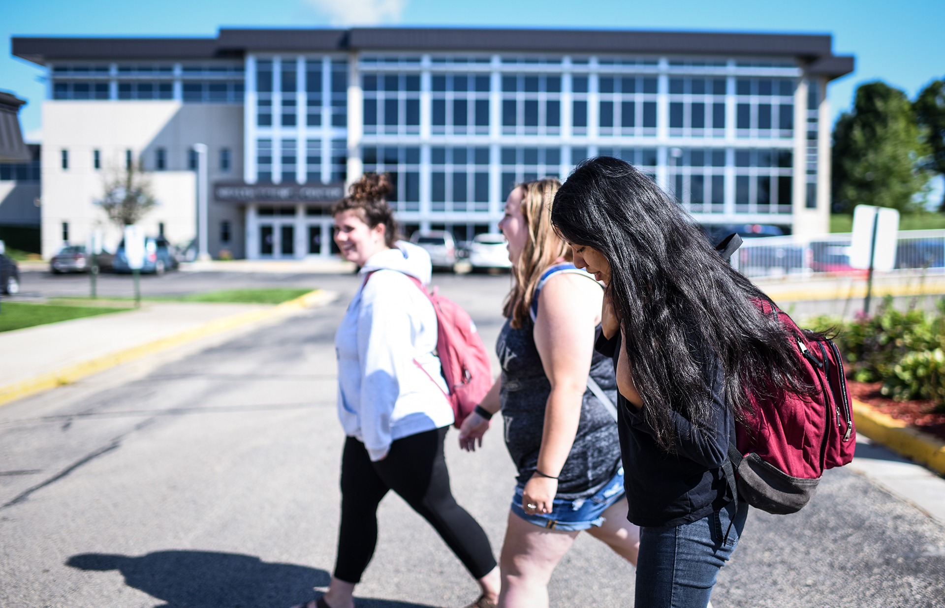 Three female students walking into a building