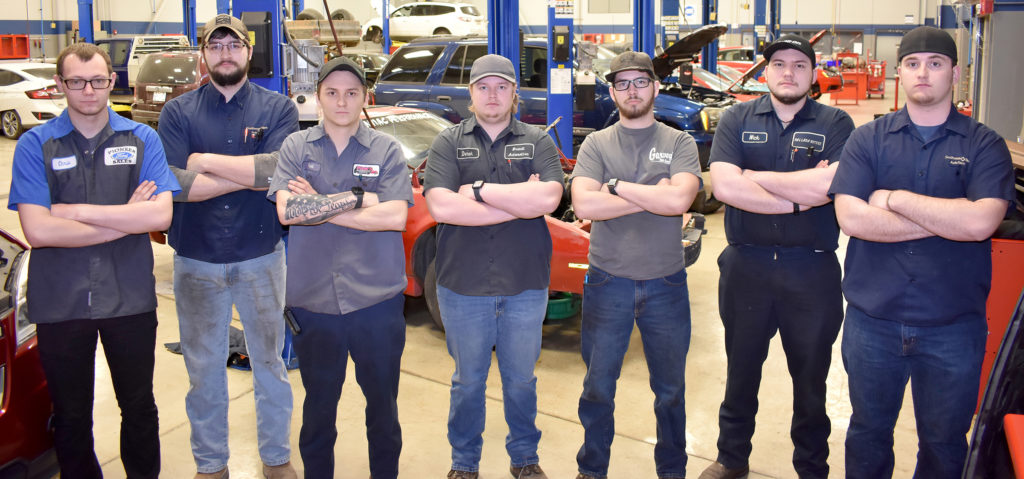 Seven males students in a row in auto shop