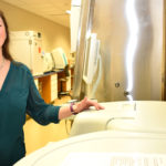 Female student standing next to medical lab equipment.