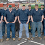 Students and two instructors outside in two rows. Two tractors behind.