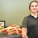 Female student standing next to model of meat cuts.