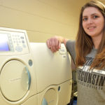 Female student standing next to medical lab equipment.