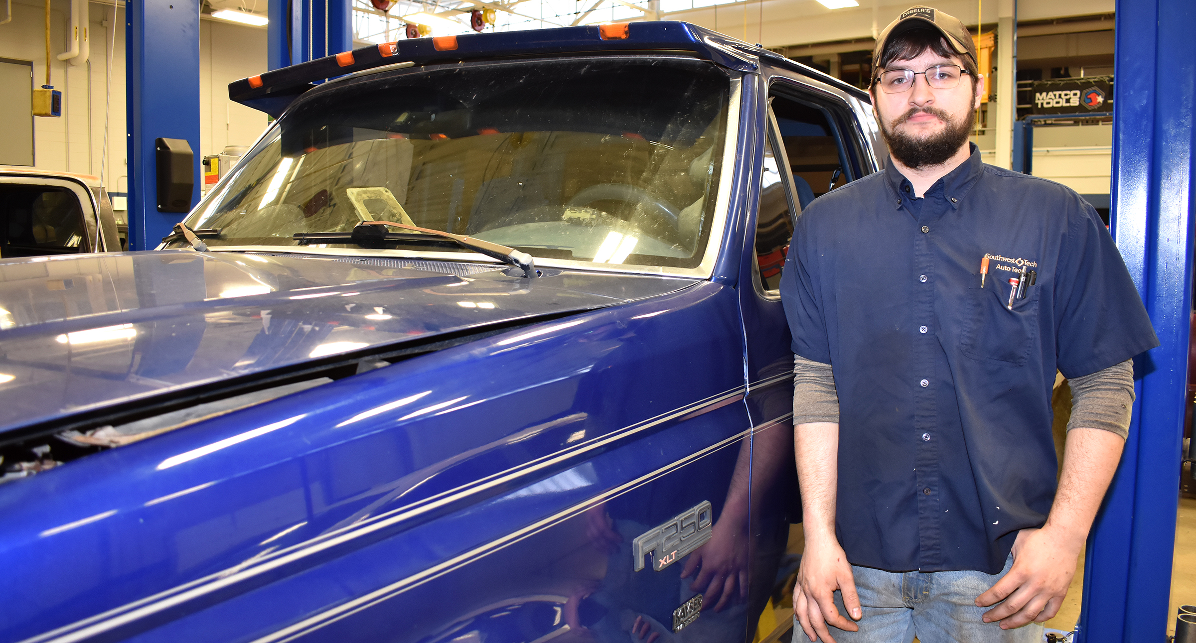 Male student standing in front of blue truck.