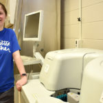 Female student standing next to medical lab equipment.