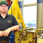 Male ag power student in front of engine.