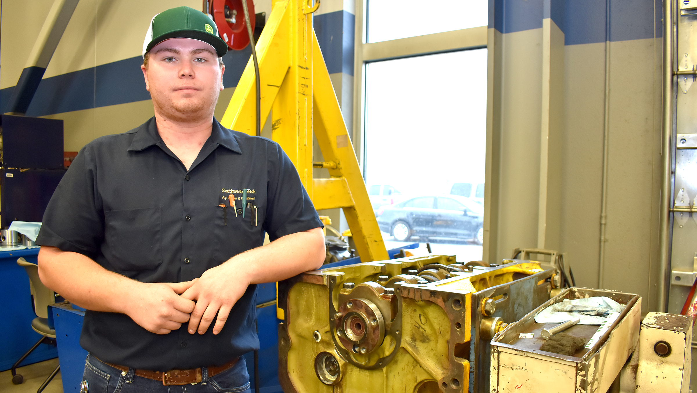 Male ag power student in front of engine.