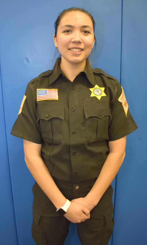Female standing in police uniform.