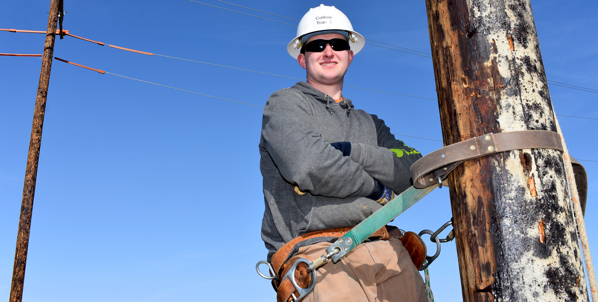 Male student wearing hard hat on electrical pole.