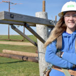 Female student standing in field wearing hard hat