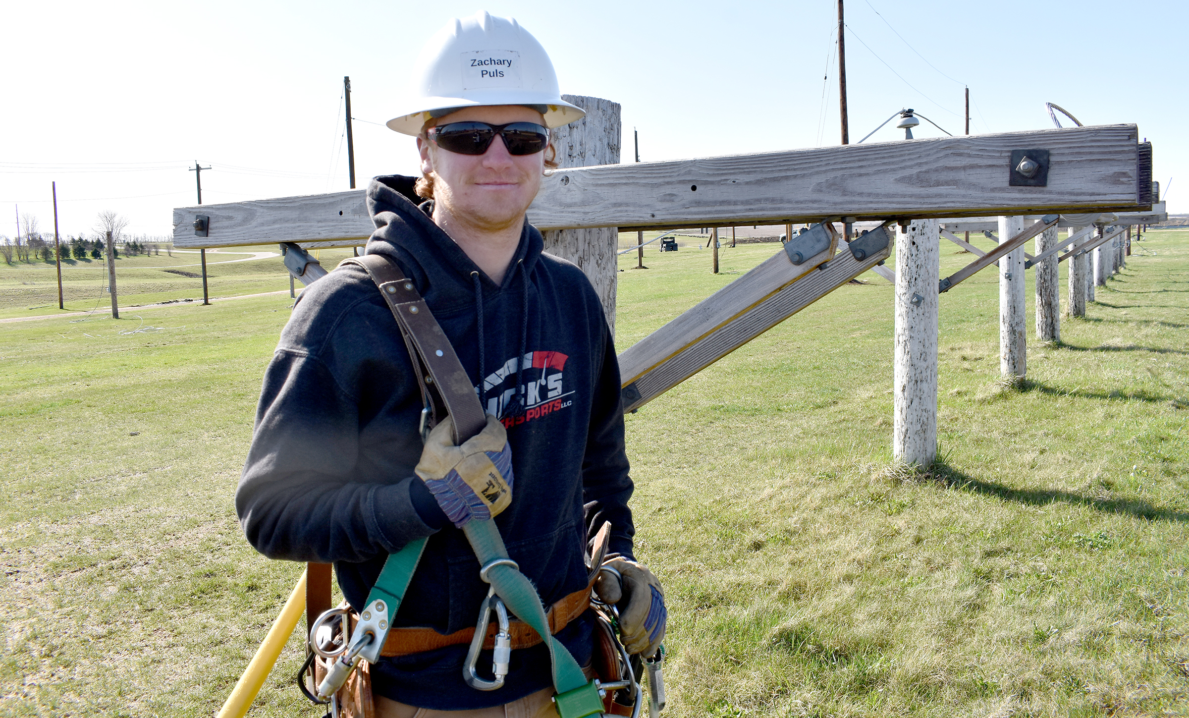 Male student wearing hard hat next to electrical equipment.