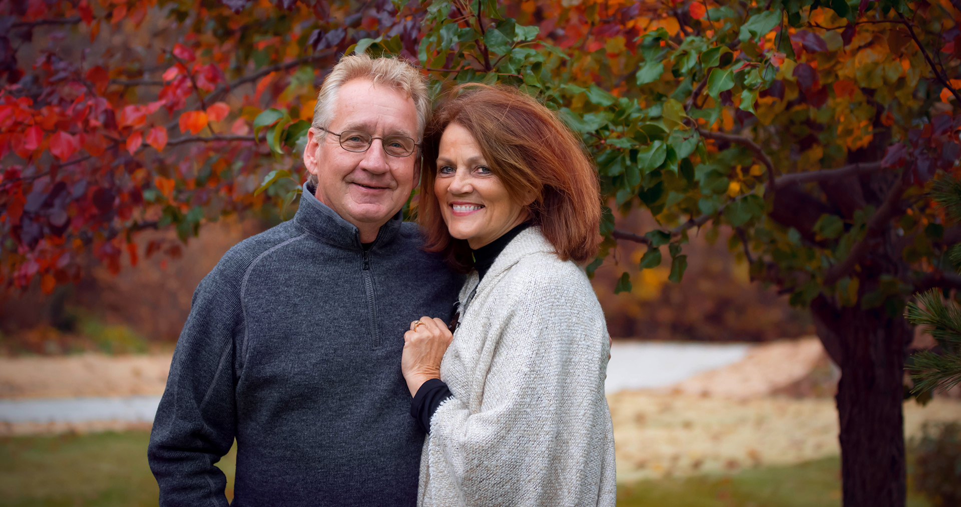 Couple looking at camera with colorful trees in background