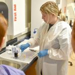 Livie teaching younger students, wearing a white protective lab coat.