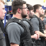 CJ students standing in line, wearing protective gear.