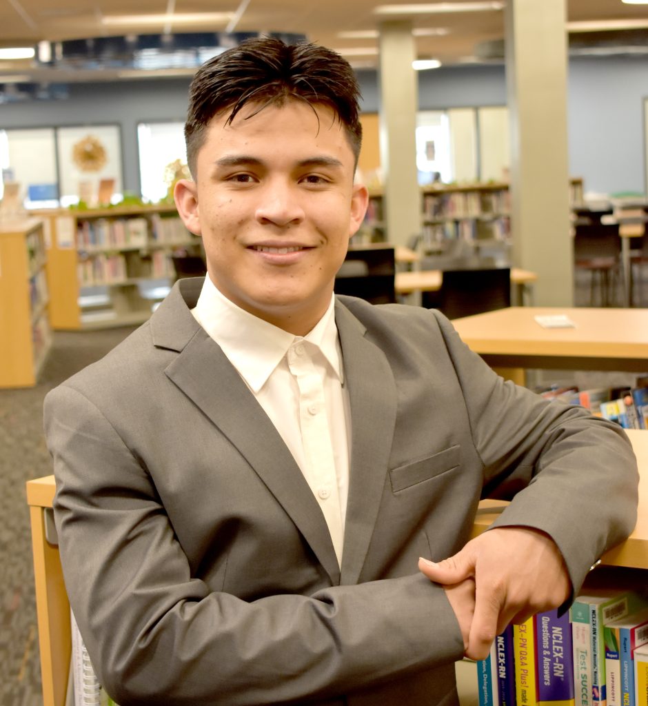 Edwin leaning against a bookshelf in the library.