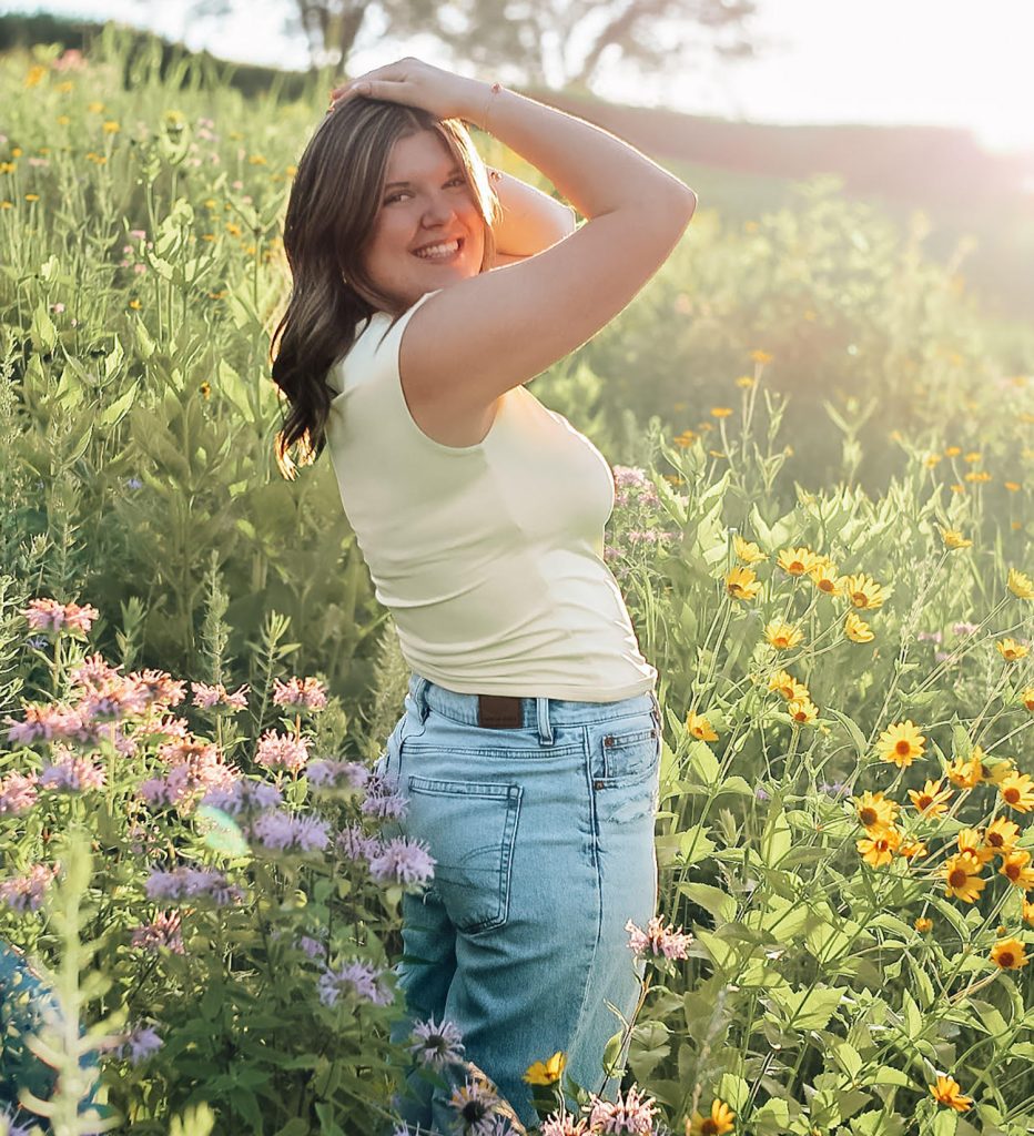 Maddie standing in a flowery field.