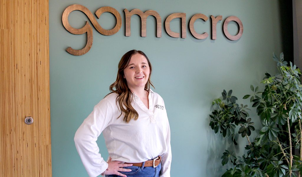 Cassidy standing in front of a wall with GoMacro sign.